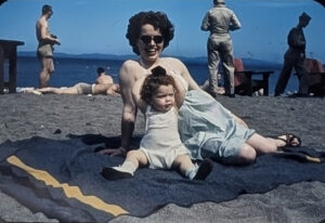 Smiling woman on a beach with toddler on beach blanket
